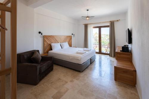 a bedroom with a bed and a chair and a television at TERRA GAİA Hotel in Gokceada Town
