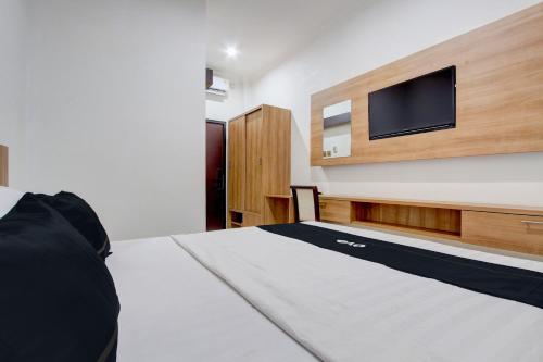 a bedroom with a bed and a tv on a wall at Capital O 93266 Palmier Hotel in Yogyakarta