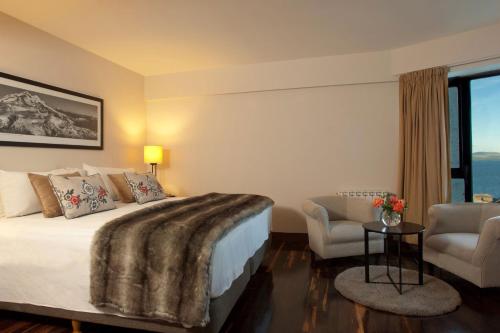 a hotel room with a bed and two chairs at Sheraton Bariloche Hotel in San Carlos de Bariloche