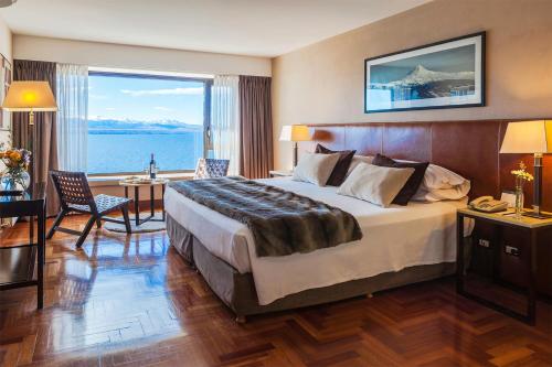 a hotel room with a large bed and a large window at Hotel Panamericano Bariloche in San Carlos de Bariloche