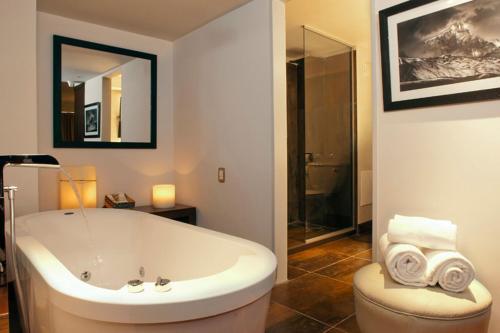 a bathroom with a white tub and a shower at Hotel Panamericano Bariloche in San Carlos de Bariloche