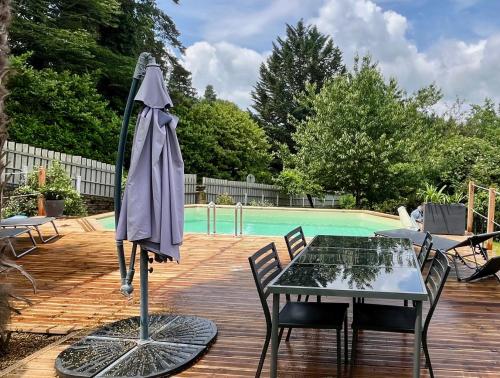 un patio con mesa y sombrilla junto a la piscina en SARLAT Centre ville - Appartement avec jardin et piscine en Sarlat-la-Canéda