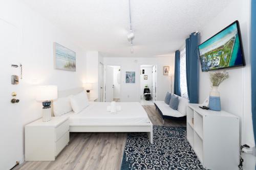 a white living room with a large white bed and a couch at Sobe Apartments in Miami Beach