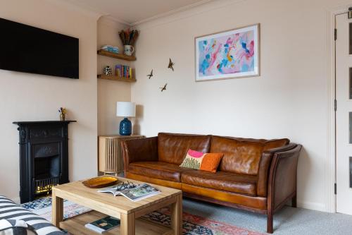 a living room with a brown leather couch and a table at The Lorelei 2BR Mid-Century Modern Stylish Apartment in Brighton & Hove