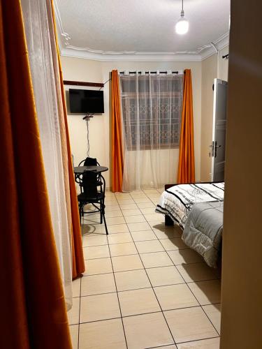 um quarto com cortinas cor de laranja, uma cama e uma mesa em Studio room entebbe em Entebbe