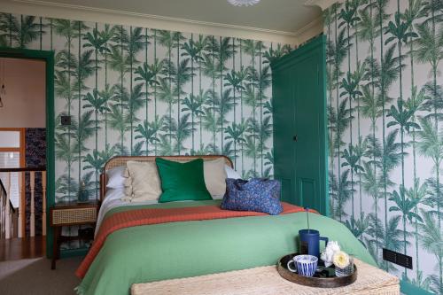 a bedroom with a green bed with palm trees wallpaper at The Lorelei 2BR Mid-Century Modern Stylish Apartment in Brighton & Hove