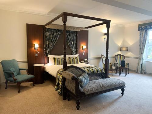 a bedroom with a four poster bed and a chair at Nunsmere Hall Hotel in Oakmere
