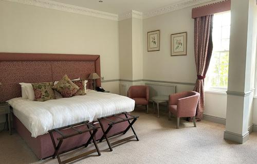 a bedroom with a bed and a chair and a window at Nunsmere Hall Hotel in Oakmere