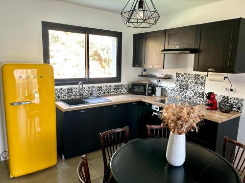 uma cozinha com uma mesa e um frigorífico amarelo em Bas de villa avec jardin idéalement situé entre Ajaccio et Porticcio em Bastelicaccia