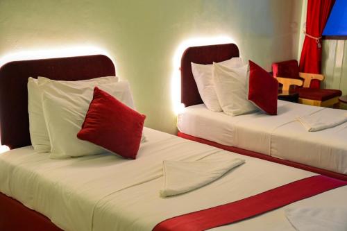 2 camas con almohadas rojas en una habitación de hotel en SIESTA HOTEL en Yibuti