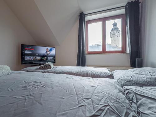 ein Schlafzimmer mit zwei Betten und einem Fernseher und einem Fenster in der Unterkunft Rathausblick – Moderne Ferienwohnung mit 2 Schlafzimmern, Küche, Bad, Waschmaschine & Trockner mitten in der Innenstadt in Leipzig
