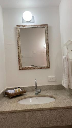 a bathroom with a sink and a mirror at Pousada Pé na Areia Guarujá in Guarujá