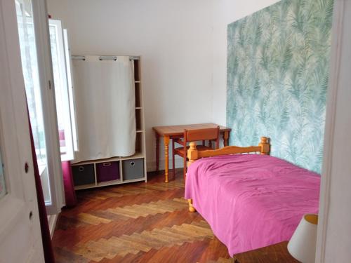 a bedroom with a bed with a pink bedspread and a table at Maison de campagne in Brinon-sur-Beuvron