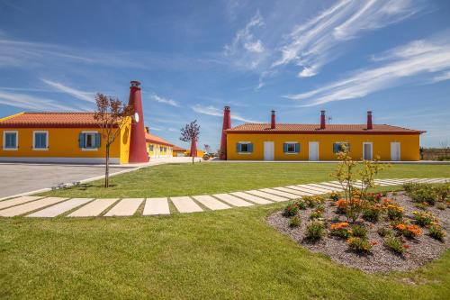 a house with two red chimneys and a yard with flowers at Resort Rural Quinta do Carrascal in Santarém
