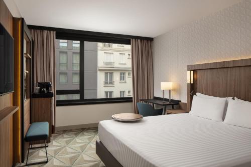 a hotel room with a bed and a large window at Courtyard by Marriott Paris Porte de Versailles in Issy-les-Moulineaux