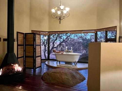 een badkamer met een bad in een kamer met een open haard bij Tholo Private Game Lodge in Bela-Bela
