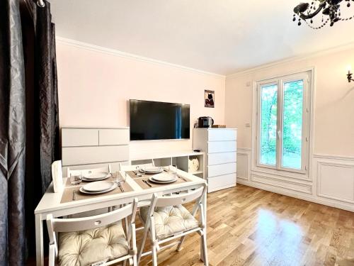 a living room with a table and chairs and a tv at Appartement à côté des épreuves olympiques in Pierrefitte-sur-Seine