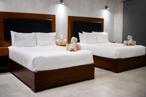 two beds in a hotel room with white sheets at Hotel Casa Tortuga Tulum - Cenotes Park Inclusive in Tulum