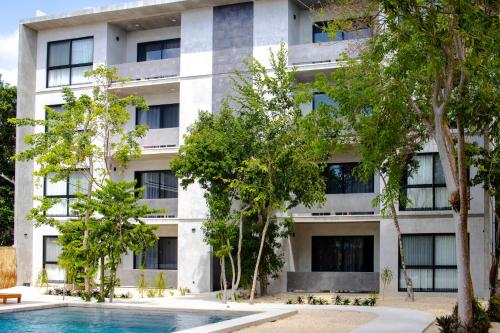 un edificio de apartamentos con piscina frente a él en Hotel Casa Tortuga Tulum - Cenotes Park Inclusive en Tulum