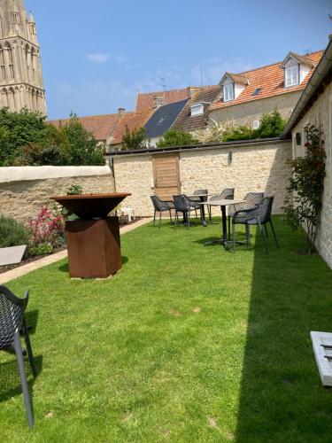 a group of chairs and tables in a yard at JunoGîte - Résidence in Bernières-sur-Mer