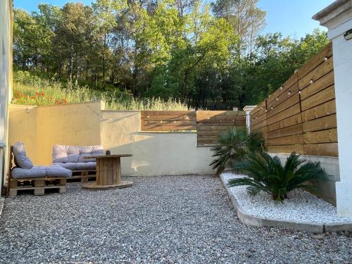 a patio with two chairs and a table and a fence at La Parenthèse Maisonnette avec Jacuzzi in Le Luc