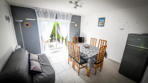 une cuisine avec une table, des chaises et un réfrigérateur dans l'établissement Charmant deux pièces rez de chaussée, à Cabourg