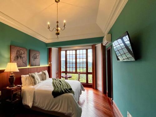 1 dormitorio con paredes verdes, 1 cama y ventana en Aroso Paço Hotel, en Pedra Azul