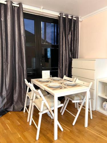 - une table à manger et des chaises blanches dans la chambre dans l'établissement Appartement à côté des épreuves olympiques, à Pierrefitte-sur-Seine