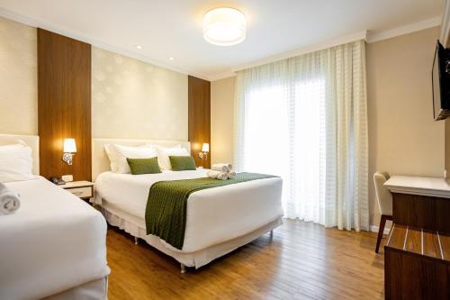 a hotel room with two beds and a window at Hotel Jardins da Colina in Nova Petrópolis