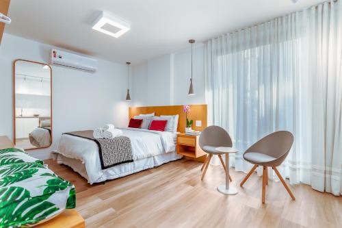 een slaapkamer met een bed, een bureau en 2 stoelen bij Unhotel - Bossa Design Studios Ipanema, Perto da Praia in Rio de Janeiro