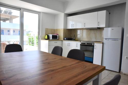 cocina con mesa de madera y electrodomésticos blancos en Roseberry Studios en Faliraki