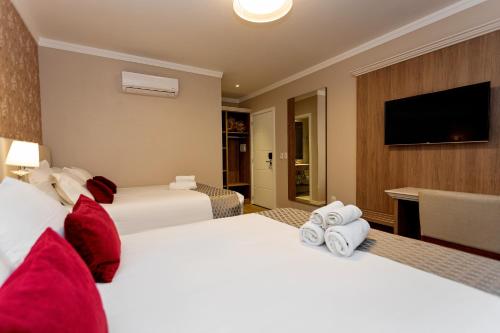 a hotel room with two beds and a flat screen tv at Hotel Jardins da Colina in Nova Petrópolis