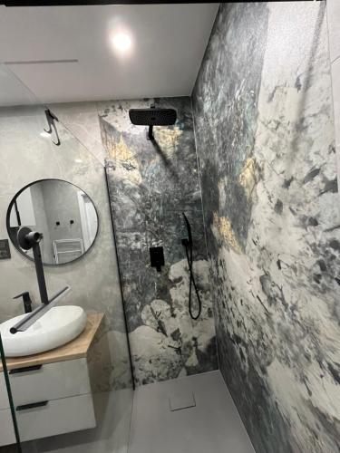 a bathroom with a shower and a sink and a mirror at Apartament Amelium Darmowy podziemny parking in Suwałki