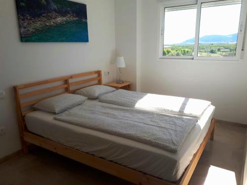 a bed in a bedroom with two windows at La Bonita Ador Apartamento in Ador