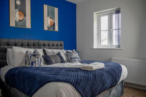 a bedroom with a bed with a blue wall at Short Stays, Free Parking, Contractors, Families - Large Home in Durham