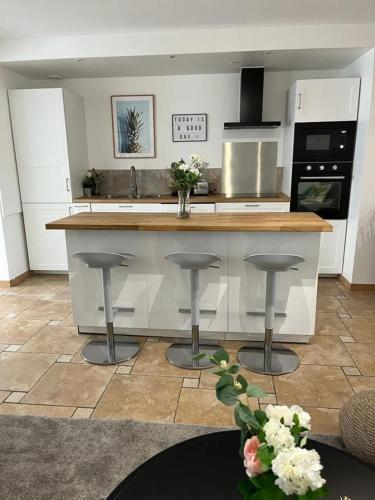 une cuisine avec un comptoir et deux tabourets dans l'établissement A 100 m2 appartement with terrasse near the beach, à Barneville-Carteret