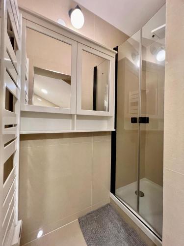 un dressing avec des armoires blanches et une douche en verre dans l'établissement Appartement à côté des épreuves olympiques, à Pierrefitte-sur-Seine