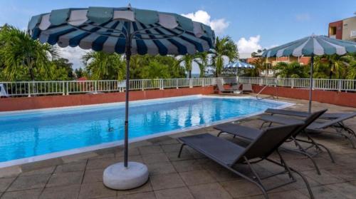 a swimming pool with two chairs and an umbrella at Appartement piscine et vue mer in Tartane