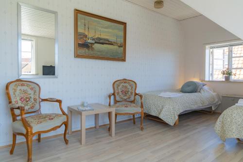 a room with a bed and two chairs and a table at Pension Slægtsgaarden in Allinge