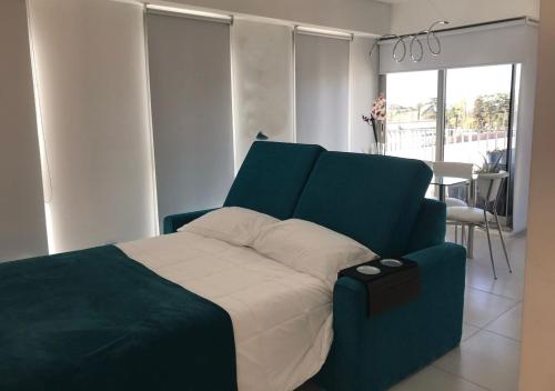 a bedroom with a bed with a blue head board at Estudio en Puerto Norte con PILETA incluida y COCHERA opcional in Rosario