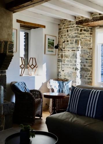 un salon avec un canapé et un mur en pierre dans l'établissement Traditional Normandy farmhouse only 3 km from the beach, à Saint-Georges-de-la-Rivière