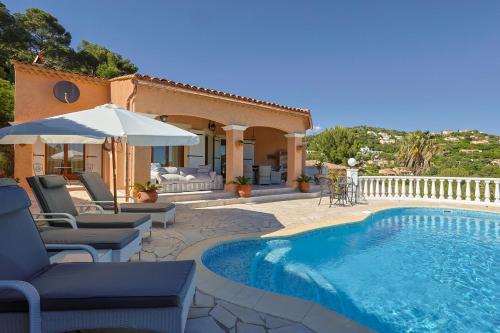 une maison dotée d'une piscine avec des chaises et un parasol dans l'établissement Luxus Villa Cristina - mit Pool und Meerblick by Riviera HomeLife, à Roquebrune-sur Argens