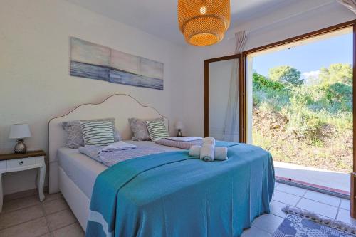 Schlafzimmer mit einem blauen Bett und einem großen Fenster in der Unterkunft Luxus Villa Cristina - mit Pool und Meerblick by Riviera HomeLife in Roquebrune-sur-Argens