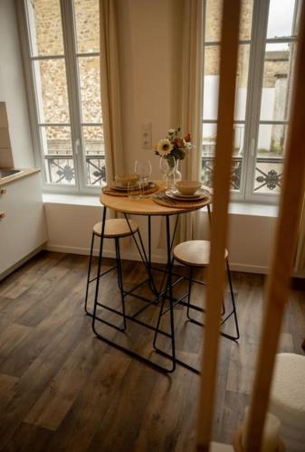 une table avec des chaises et un vase de fleurs dessus dans l'établissement Studio la halte ducale #2, à Charleville-Mézières