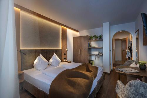 a bedroom with a large bed and a table at Almhotel Lenz in Valdaora