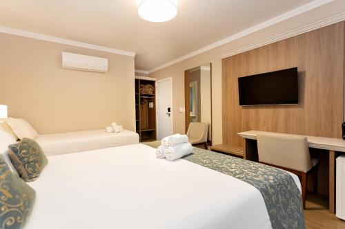 a hotel room with two beds and a flat screen tv at Hotel Jardins da Colina in Nova Petrópolis
