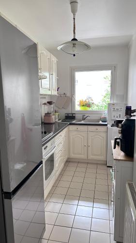 une cuisine blanche avec des armoires blanches et une fenêtre dans l'établissement Cozy apartment near La Défense & Paris La Défense Arena, à Courbevoie