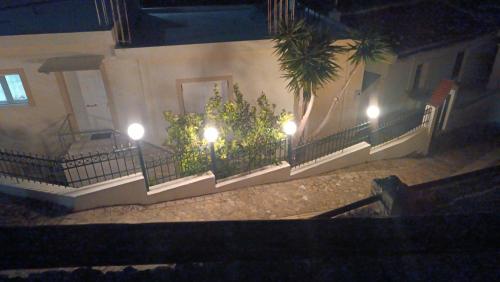 a building with a fence with plants and lights at Melina Apartment - Akoumia Village in Akoumia