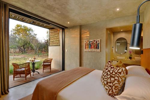 ein Schlafzimmer mit einem Bett und eine Terrasse mit einem Tisch in der Unterkunft Ngala Lodge in Klipdrift
