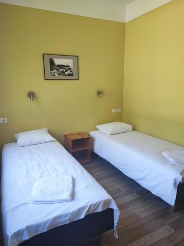 two twin beds in a room with yellow walls at Lainela puhkeküla in Käsmu